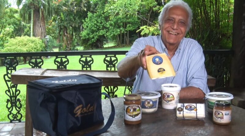 Com o fundo de uma fazenda, homem segura o queijo parmesãol