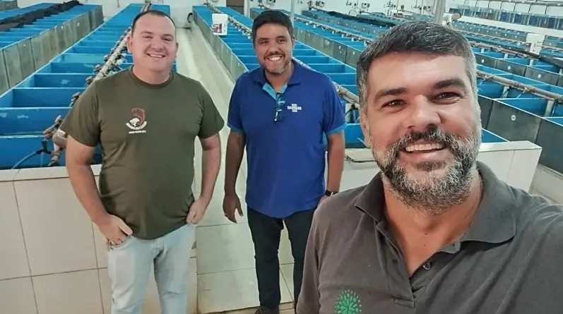 Três homens em uma self com o fundo a piscicultura
