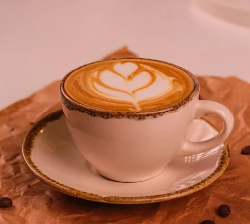 Uma xícara de café com grãos espalhados por um mesa
