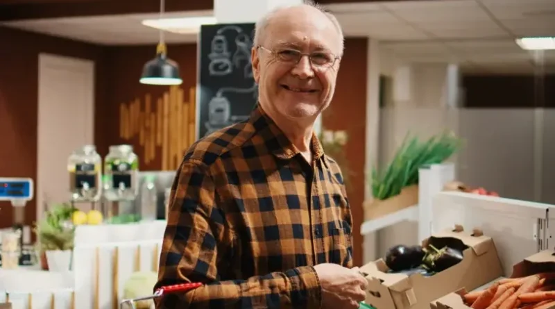 Homem de cabelos grisalhos sorrindo em um hortifruti