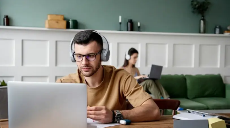 Homem com fone de ouvido e com notebook à sua frente