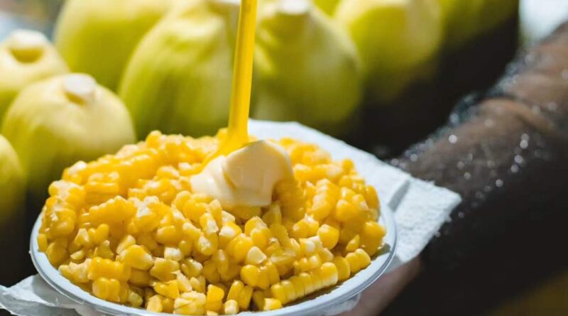 Pote de milho à frente e espigas em segundo plano