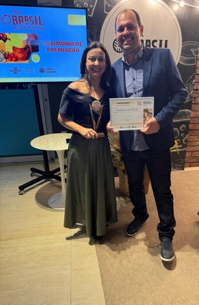 Um casal segurando um certificado de premiação 