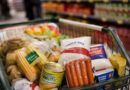 Imagem mostra carrinho de supermercado com comidas típicas de festa junina, como milho, salsicha e açúcar