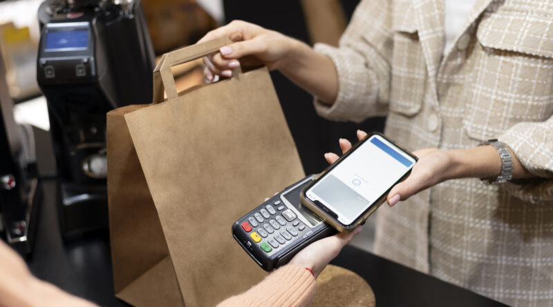 Imagem mostra pessoa usando o smartphone para pagar comprar; comércio, varejo